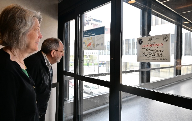 The Mayor and a constituent inspecting a skyway closure notice through a window